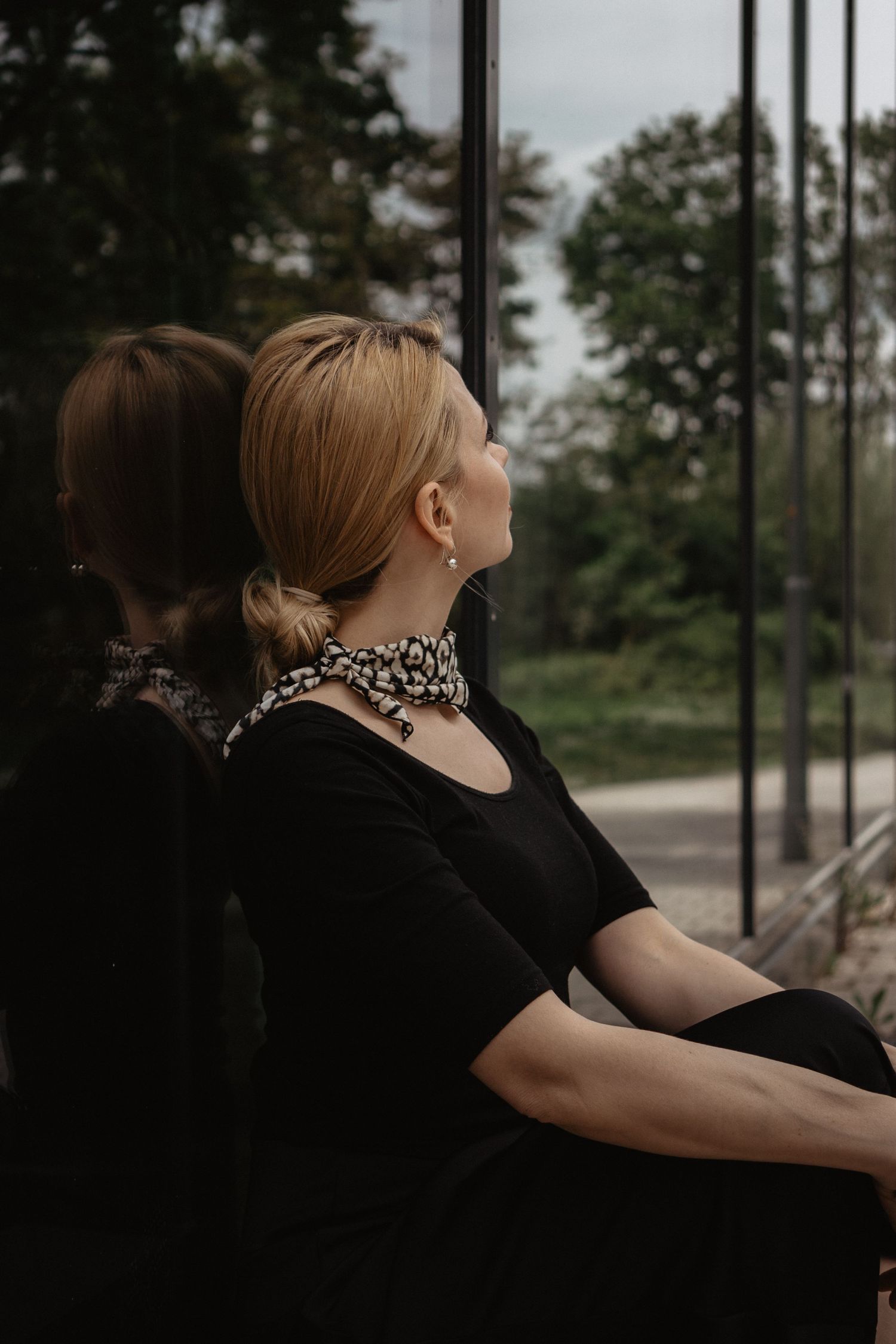 Reflective portrait with animal print scarf against window glass.