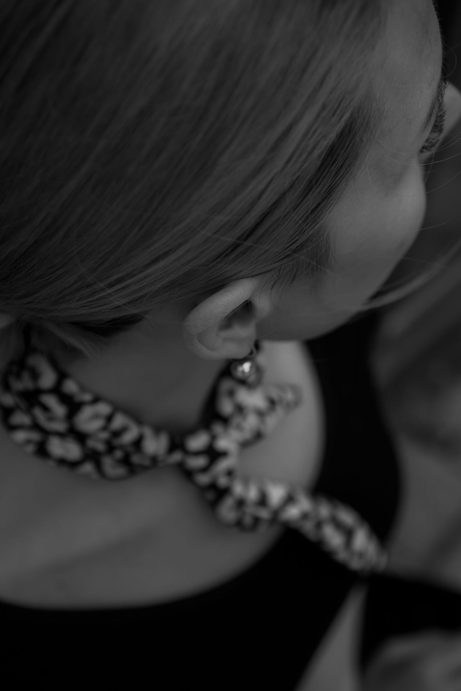 Close-up black and white detail of an intricate beaded necklace against a dark outfit.