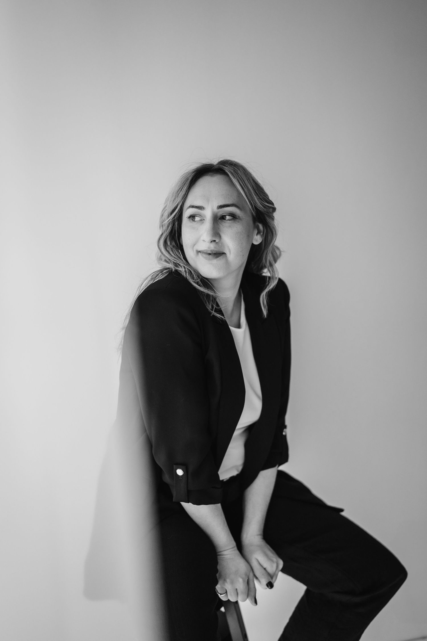 A series of artful black and white portraits showcasing a figure in elegant black attire against a minimalist white background.