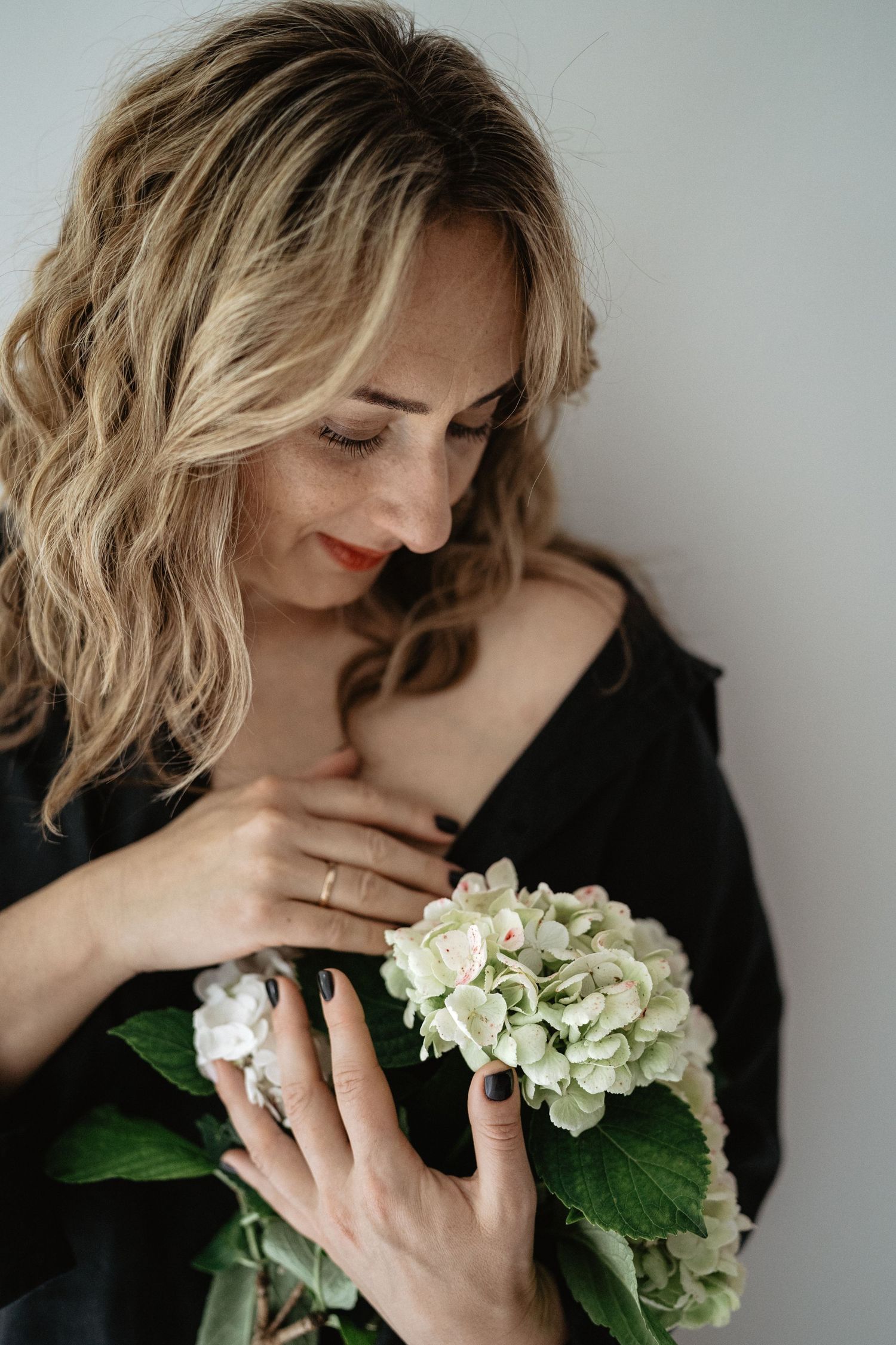 Artistic portrait series with cream hydrangea blooms against minimalist light background.