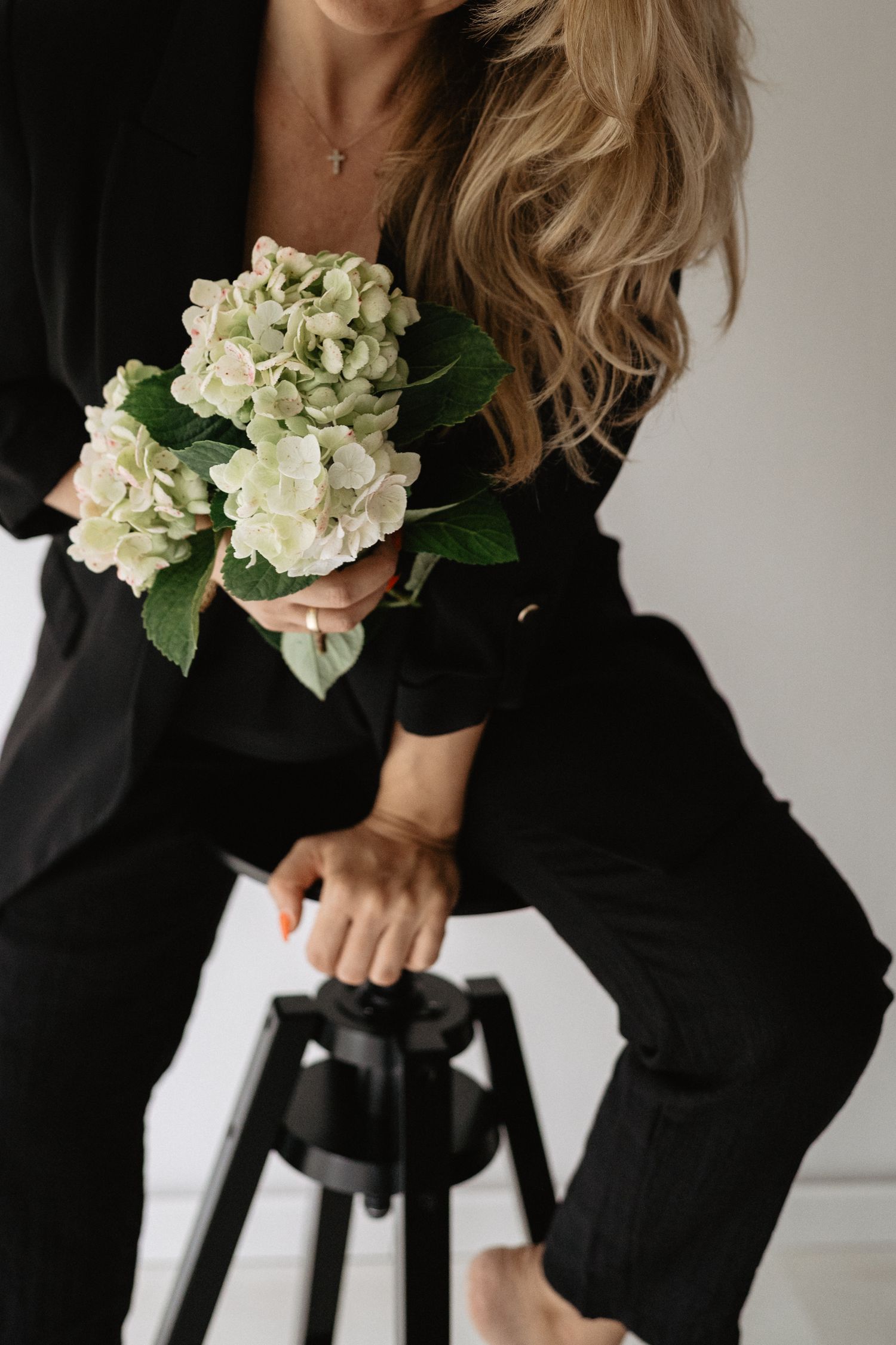 Six minimalist fashion photographs showing a black blazer with white hydrangea flowers against a neutral background.