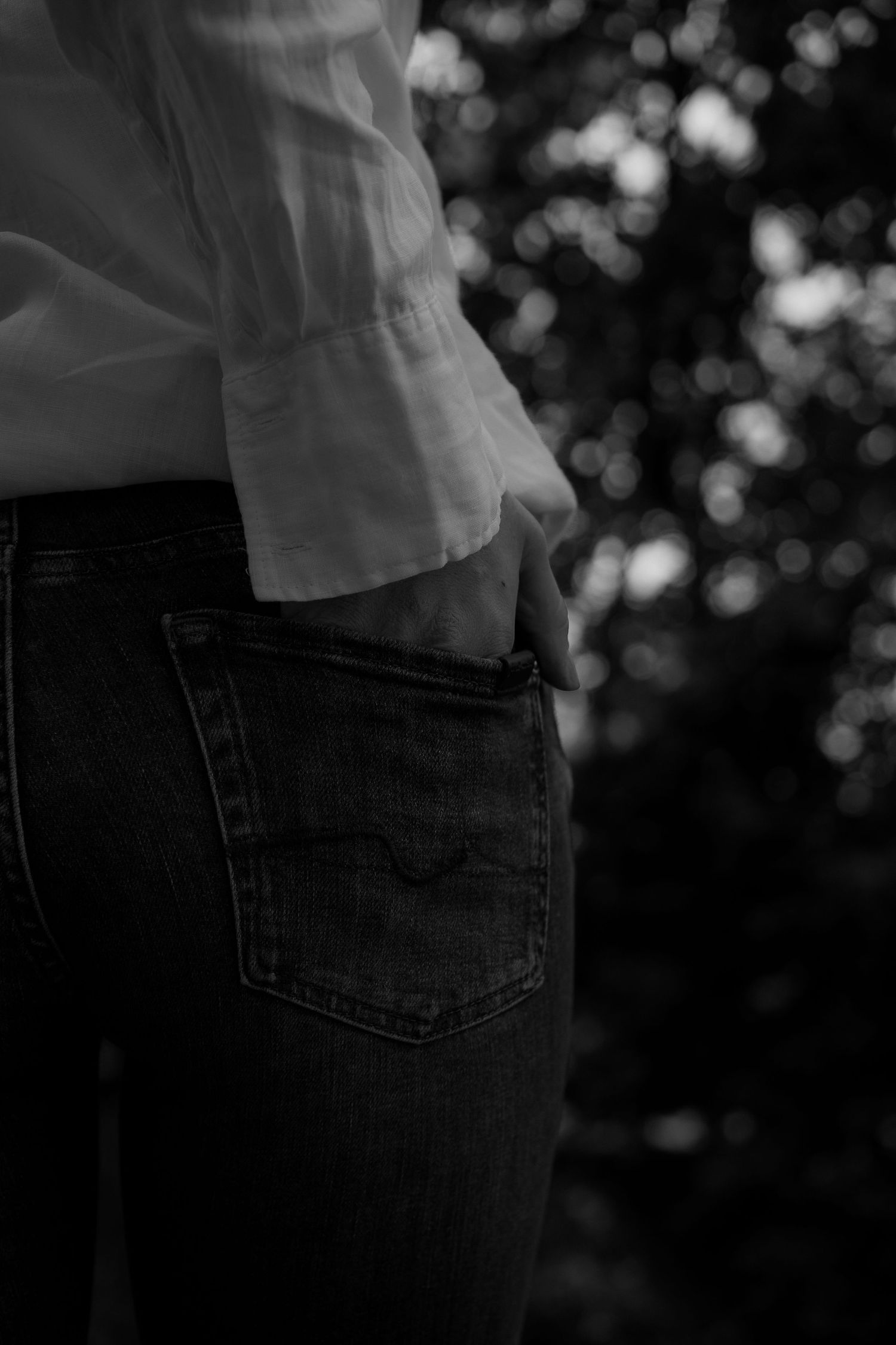Detail shot of jeans pocket and white shirt hem in monochrome.