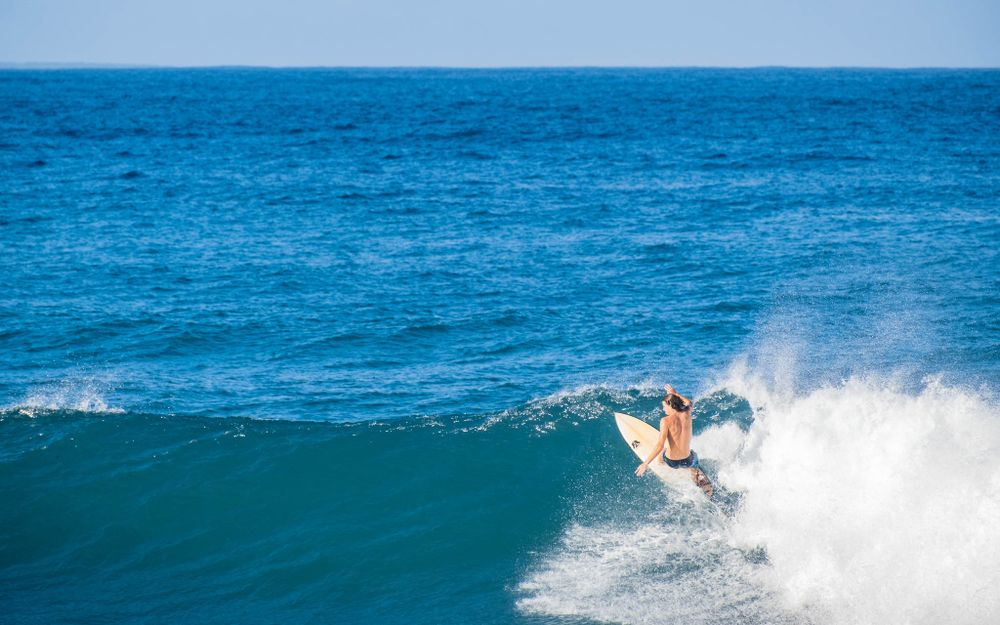 A surfer catches air while performing a trick at the top of a breaking wave.