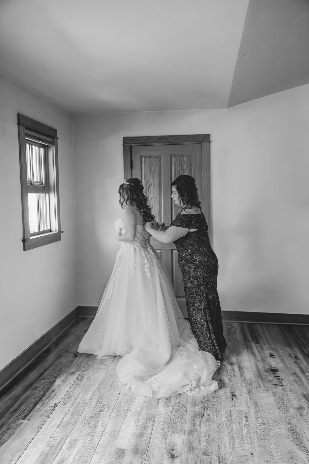 Black and white photos show bride/mother getting ready in a rustic room with wooden floors in Sheboygan, WI  with Essence Rose Photography.