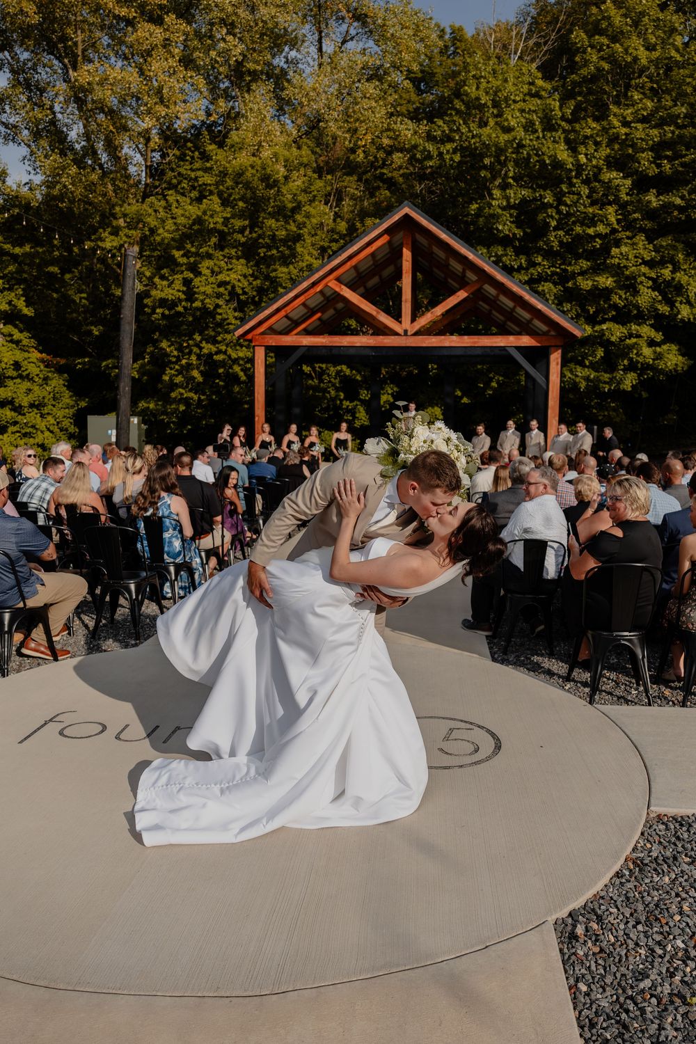 A couple performs a dramatic dip during their ceremony exit at an outdoor wedding ceremony in Kewauskum, WI  with Essence Rose Photography.