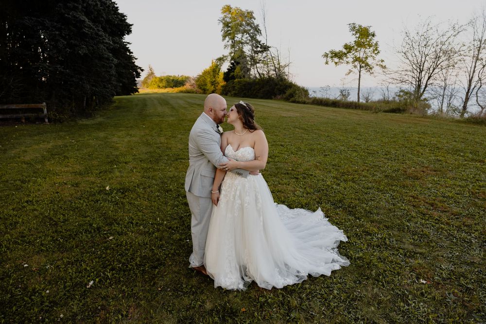 A romantic wedding couple embraces on a hillside during golden hour in Sheboygan, WI  with Essence Rose Photography.
