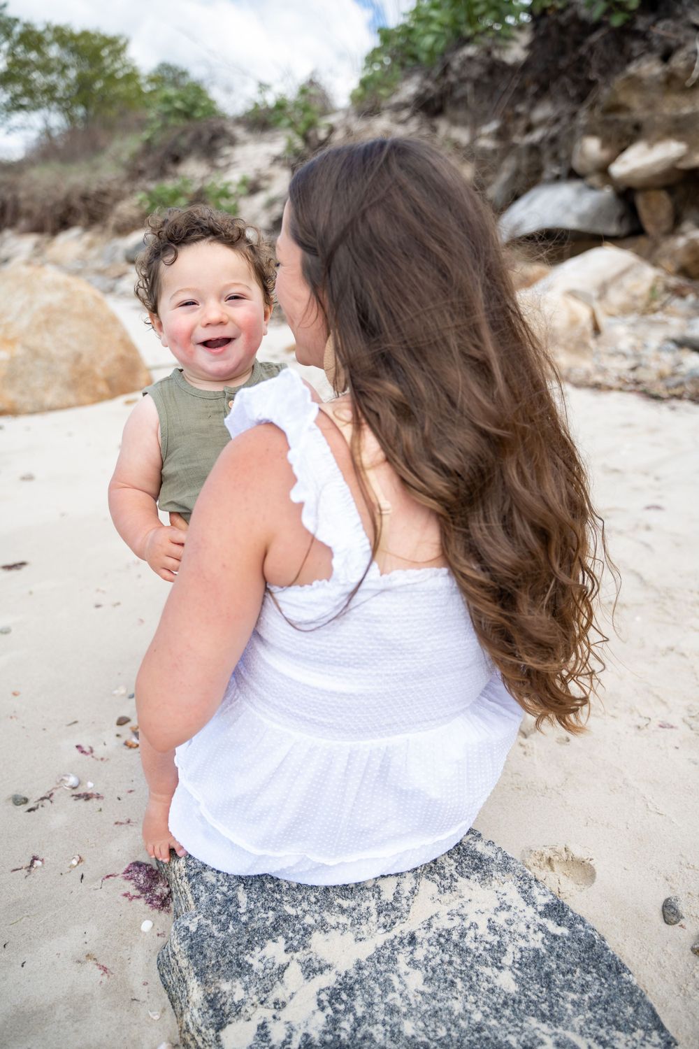 Joyful beachside moment captured with stunning coastal rocks in the background.