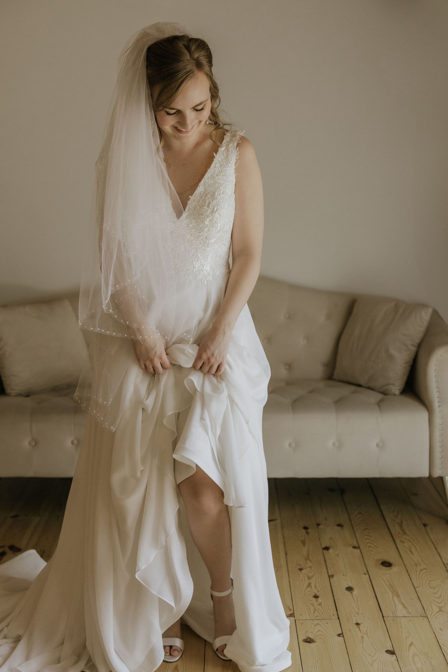 Elegant bride in white dress and lace veil poses in tropical garden with palm trees.