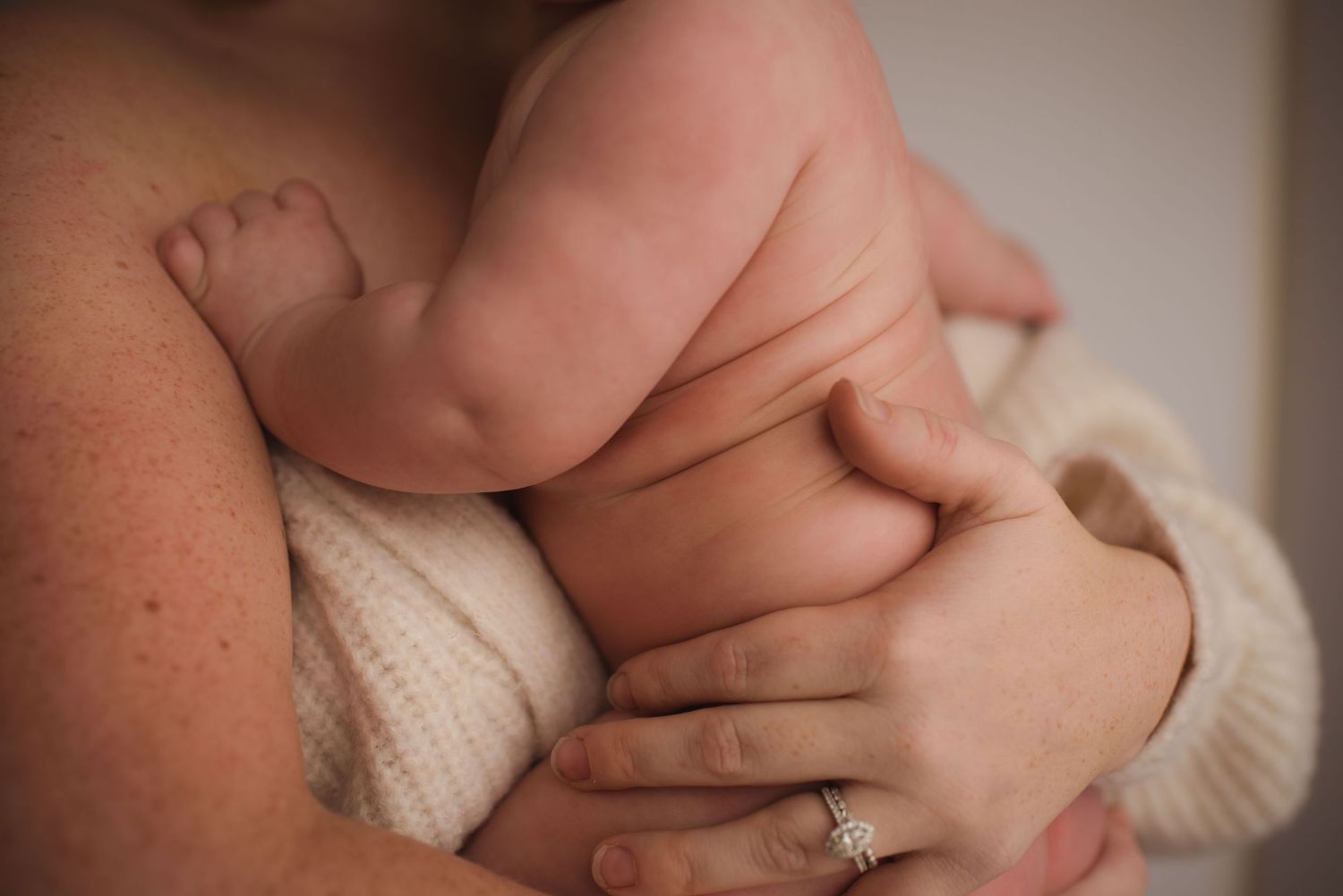 Close-up of baby's chubby hands and arms being held in soft knit sweater.