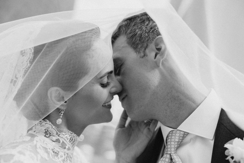Intimate black and white wedding portrait showing tender moment under veil.