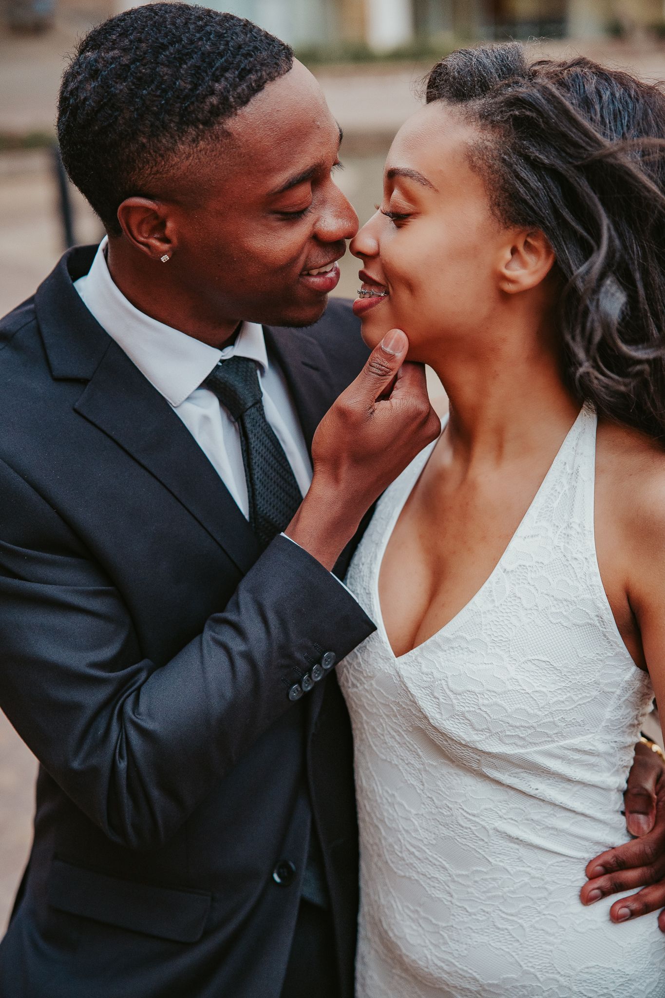 A candid outdoor portrait of a couple embracing and smiling during a photo session.