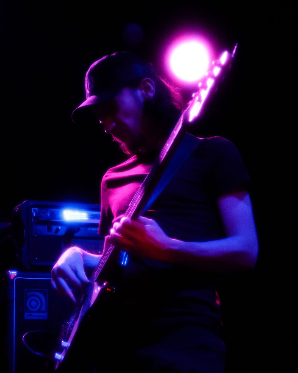 Florida concert photography of silhouetted bassist playing in dark venue.