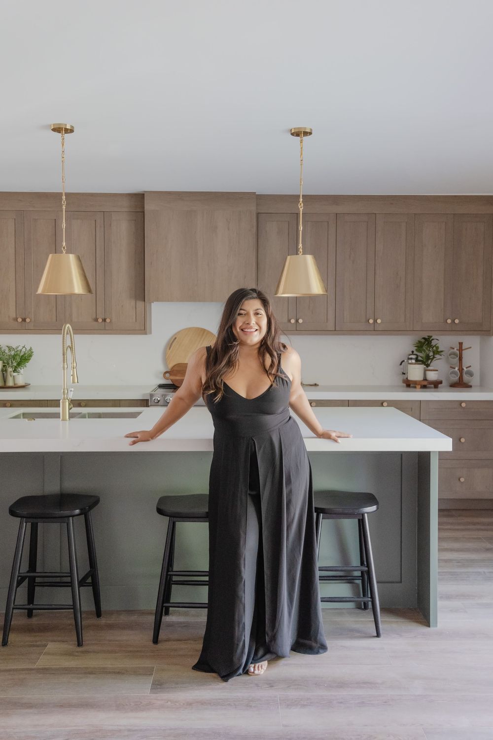 Stylish modern kitchen with taupe cabinets and brass pendant lights over white island.