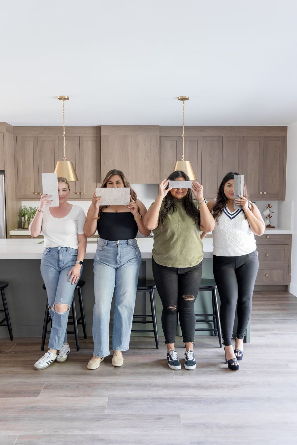 Four people having fun posing together in modern kitchen with taupe cabinets.