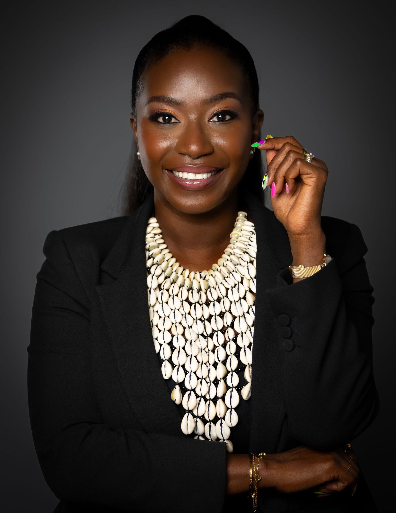 Professional headshot of woman in black blazer wearing dramatic layered white statement necklace.