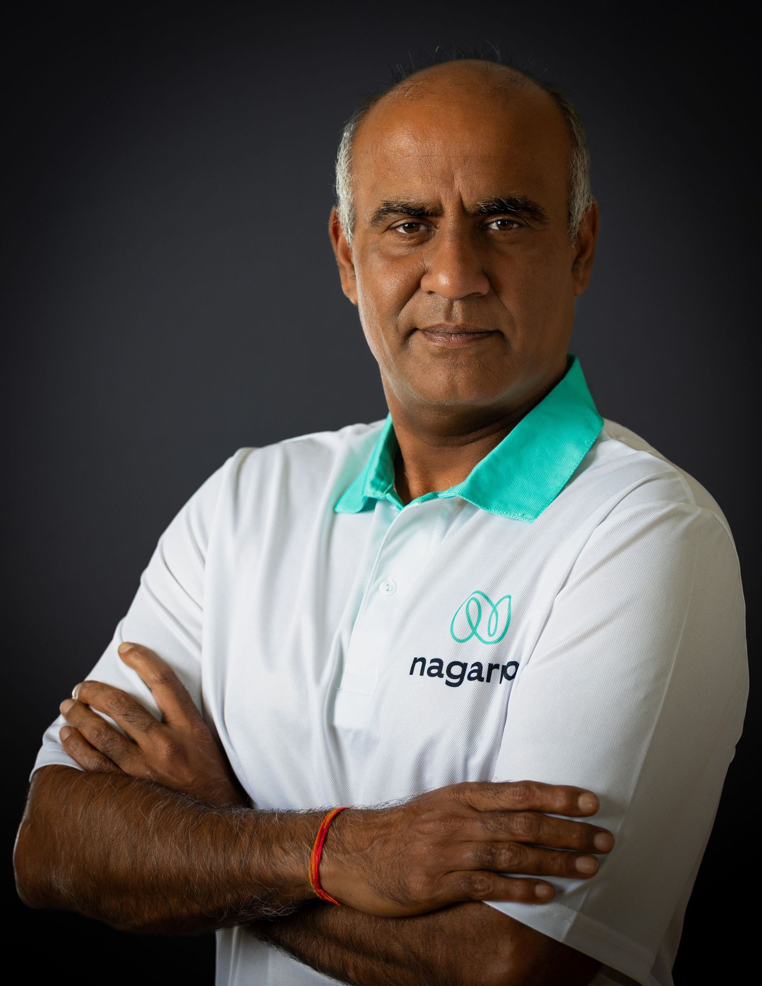 Person wearing a white polo shirt with teal collar and Nagarro company logo poses against dark background.