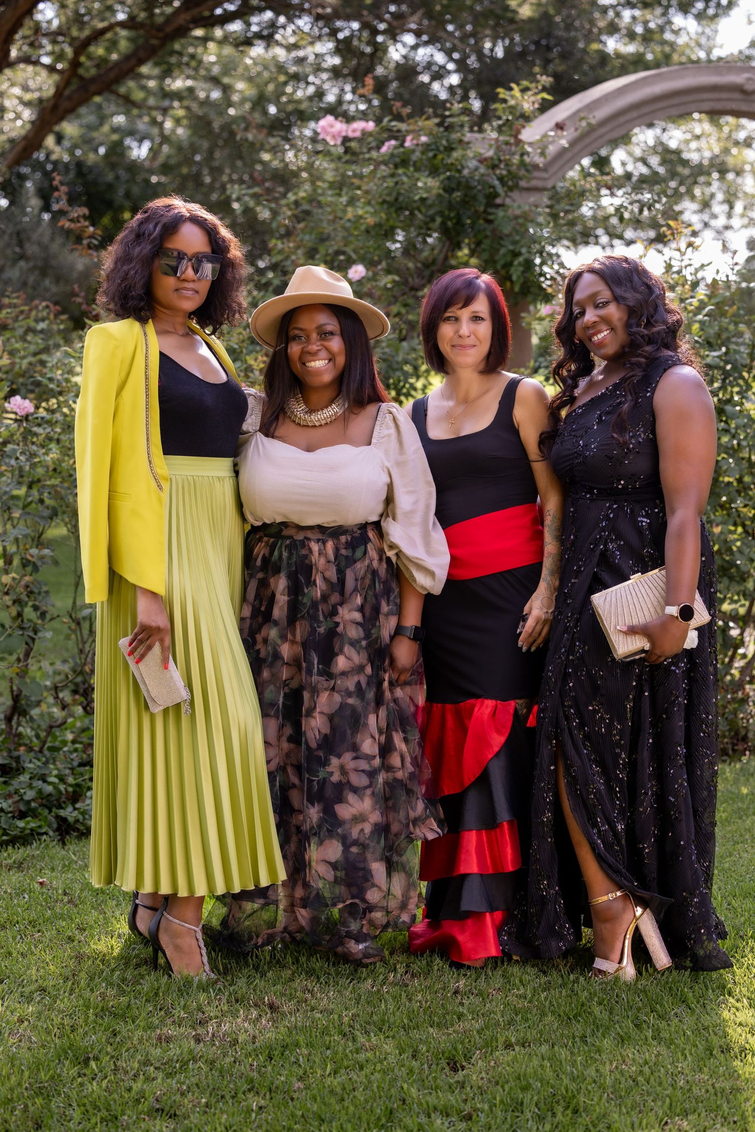 A group posed together outdoors wearing elegant evening attire in bold colors.