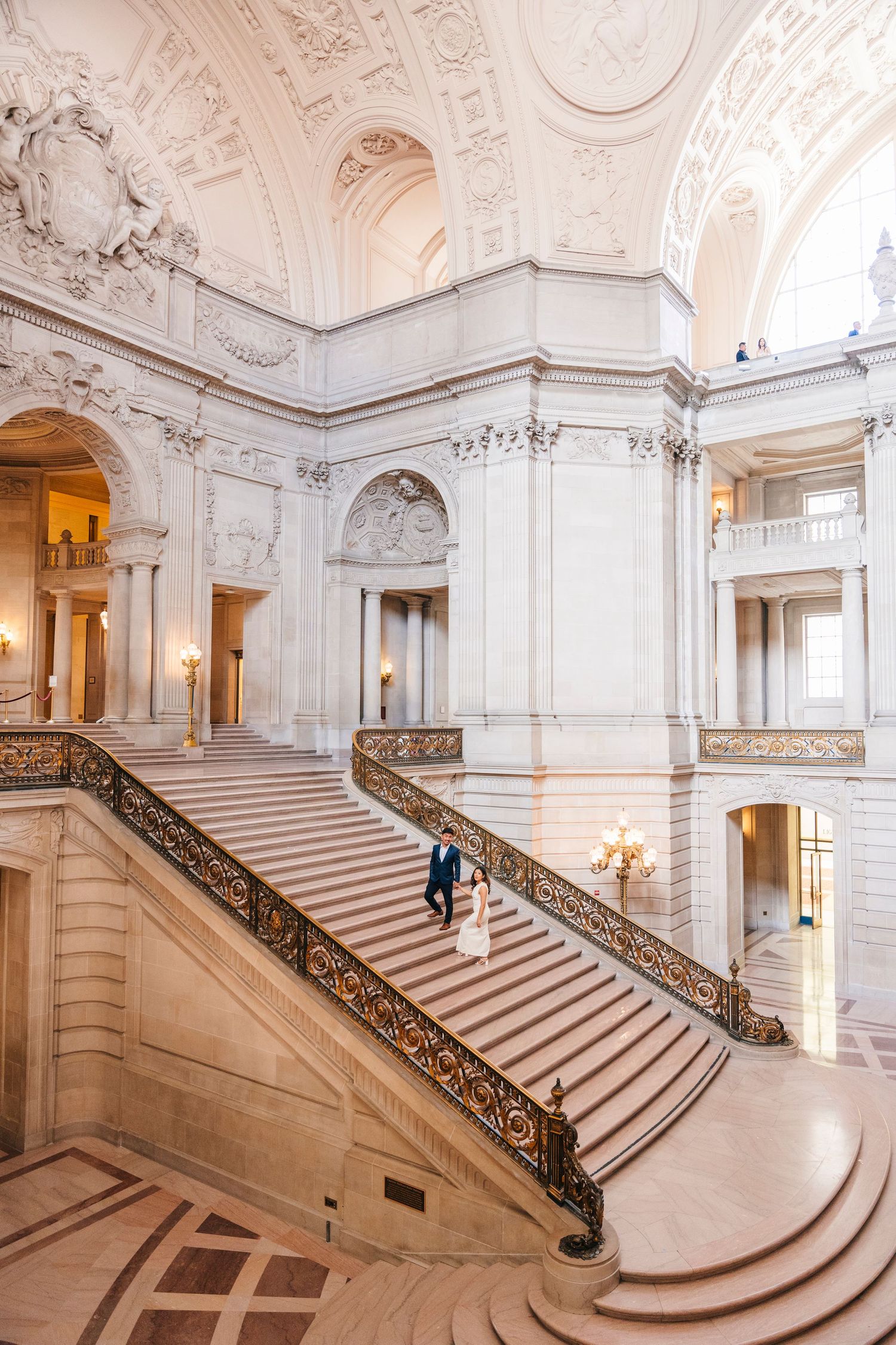 Grand marble staircase with ornate details and balustrades in historic building interior.