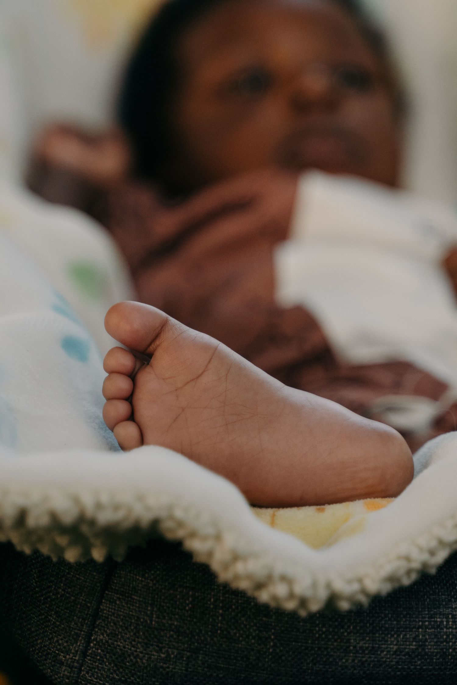 A close-up of a newborn's foot resting on a soft blanket