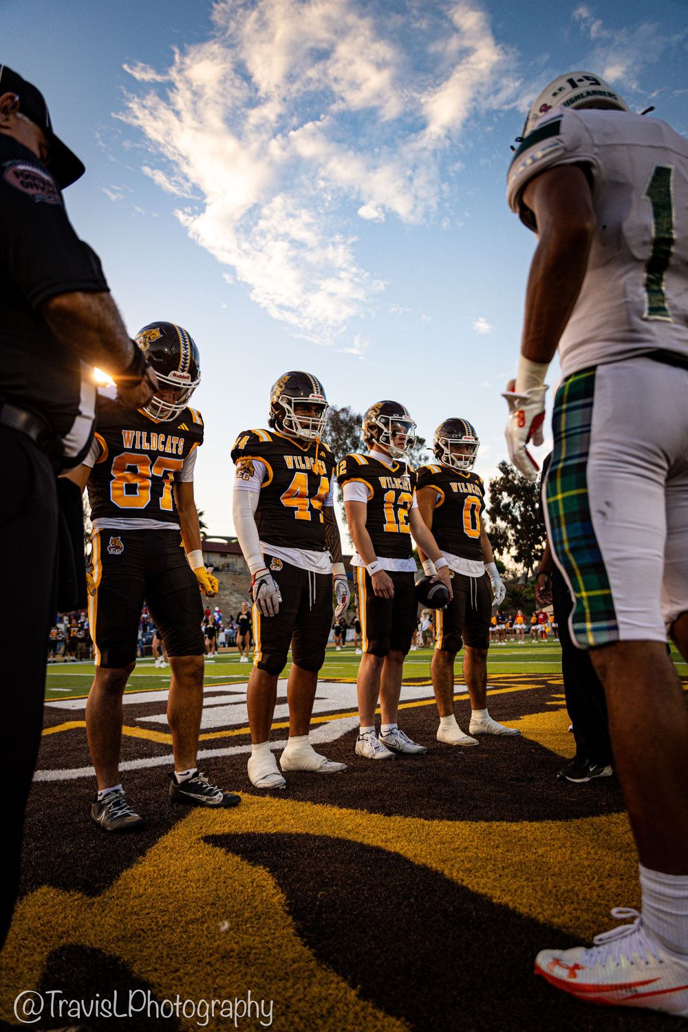 Low angle view of football players lined up on sideline during game.