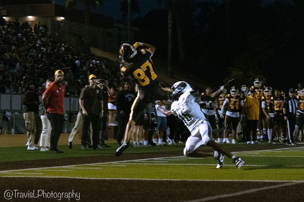 Football players in action during nighttime game on illuminated field.
