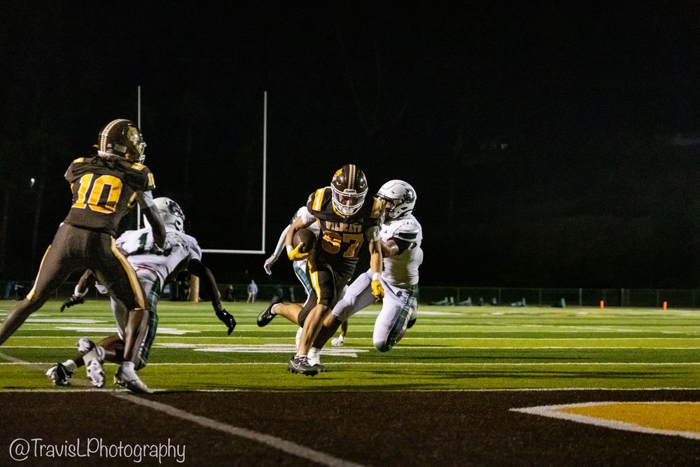 Football players line up for play during nighttime game under stadium lights.