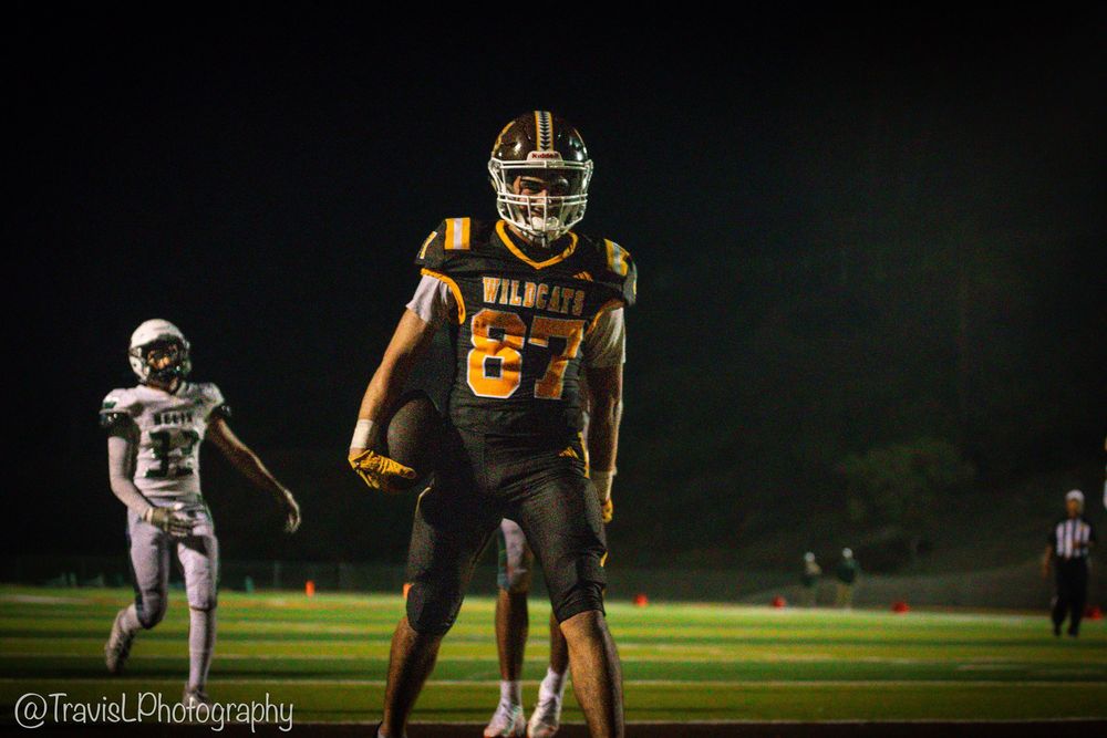 Football players in action during night game on illuminated field.