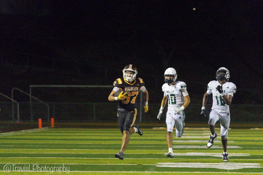 Two football teams prepare for a play during a night game on a well-lit field.