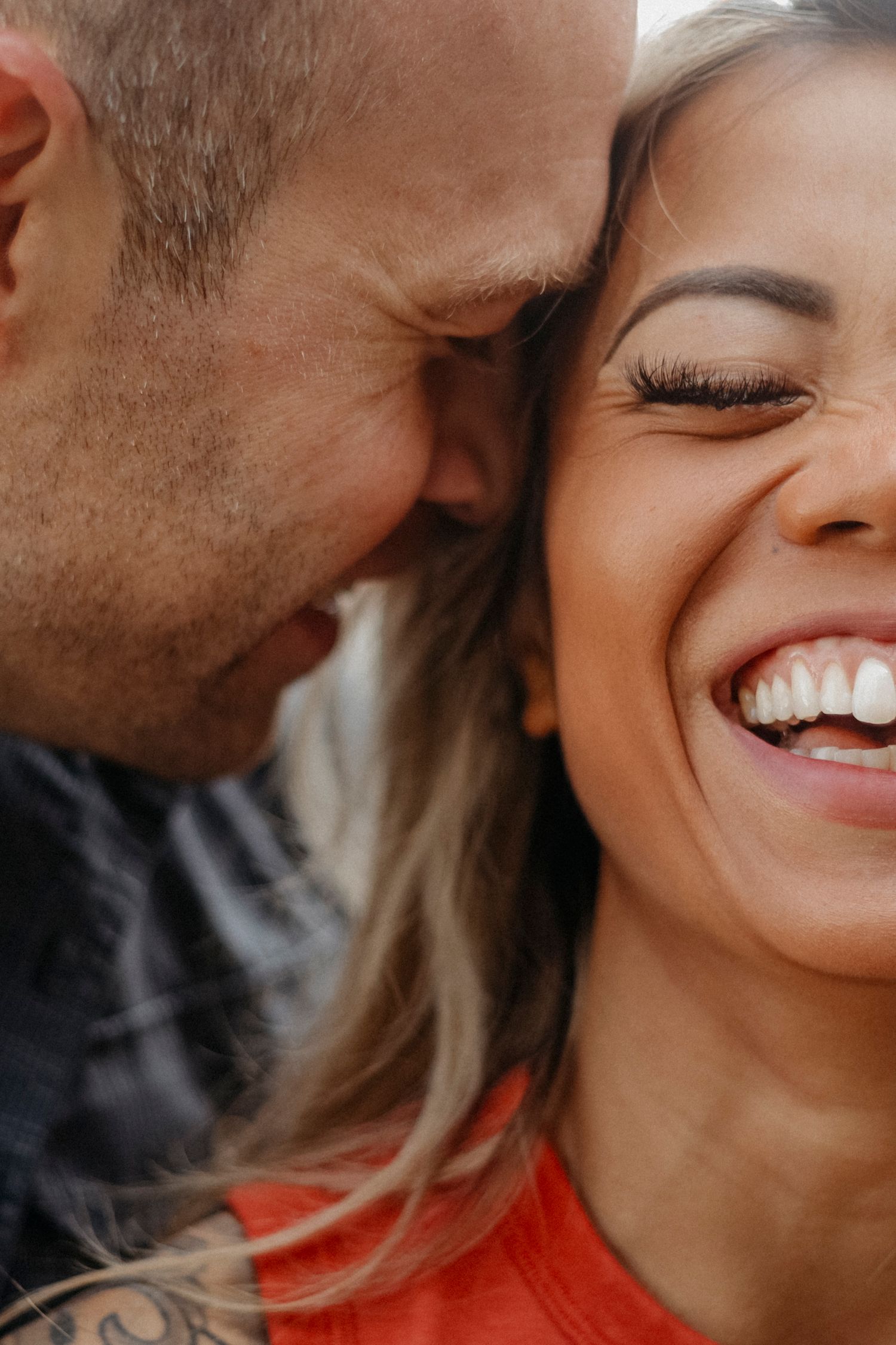 Close-up intimate portrait capturing joyful laughter and tender moment between couple.