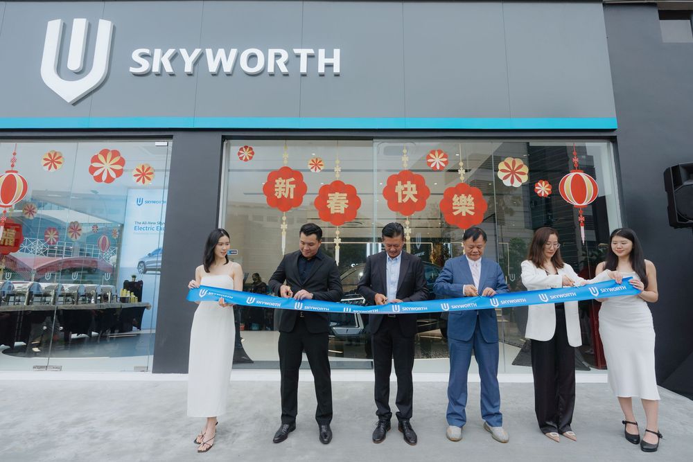 A group of people cutting a blue ribbon at a Skyworth store opening ceremony with red lantern decorations.
