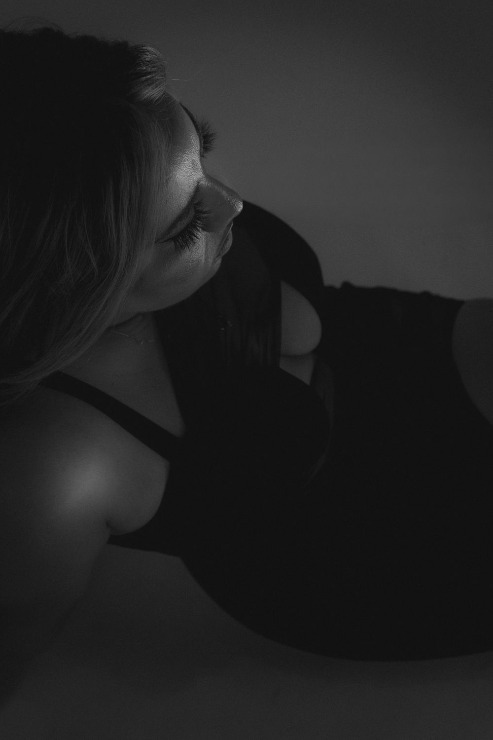 Artistic side profile portrait in dark shadows and dramatic lighting.