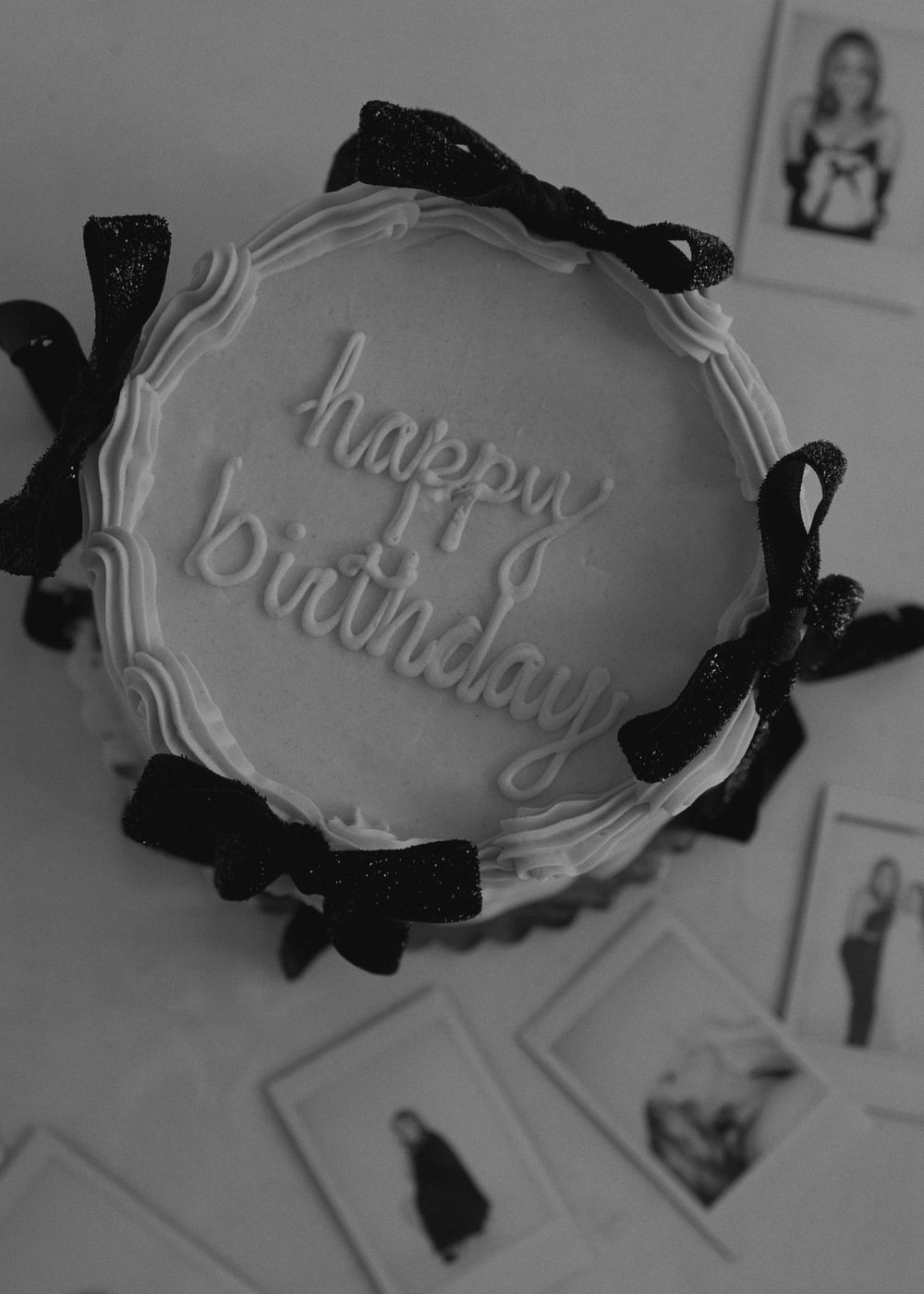 Birthday cake with white frosting and black ribbon bows decorated with Happy Birthday text.