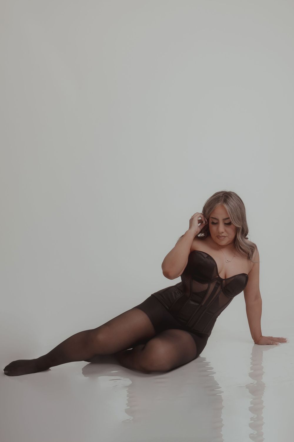 Studio portrait of person in dark lingerie posing against white background.