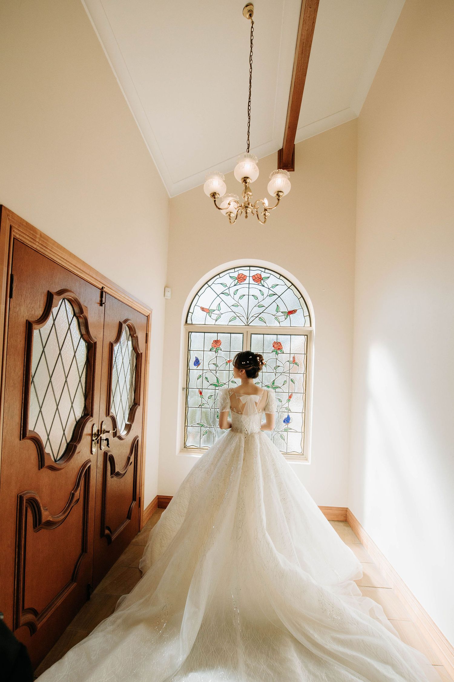 Wedding dress silhouette against stained glass window with dramatic train.