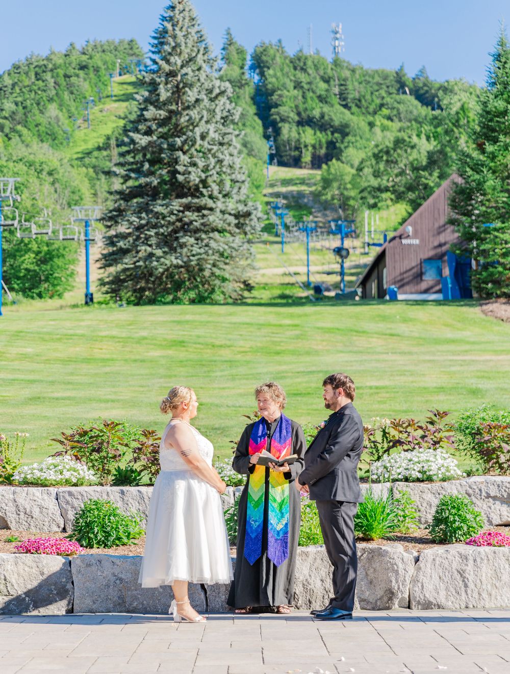 Mountain resort wedding ceremony with ski slopes and evergreens in background.