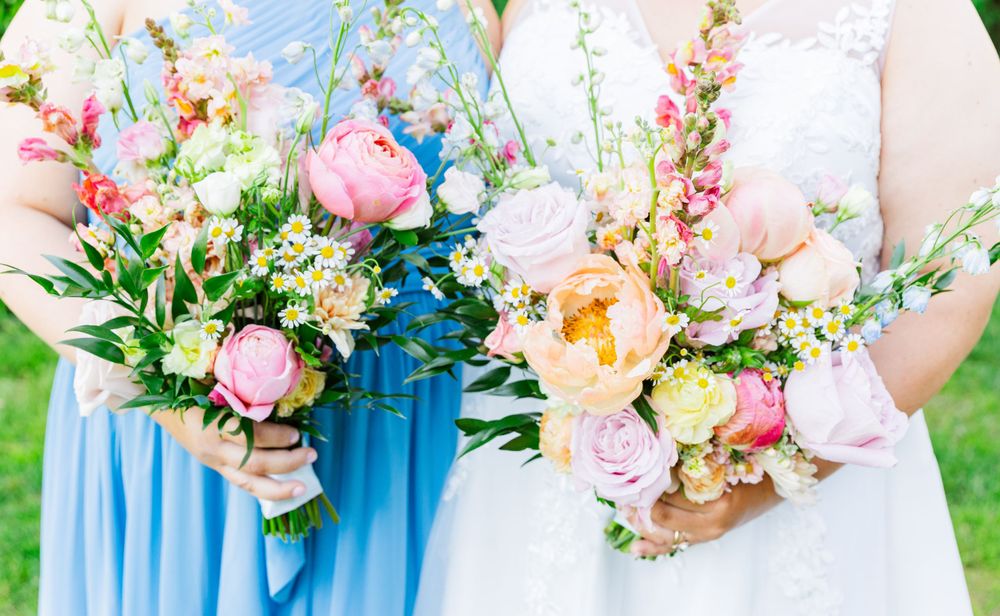 Close-up of two elegant wedding bouquets featuring pink roses, peach blooms, and delicate greenery.