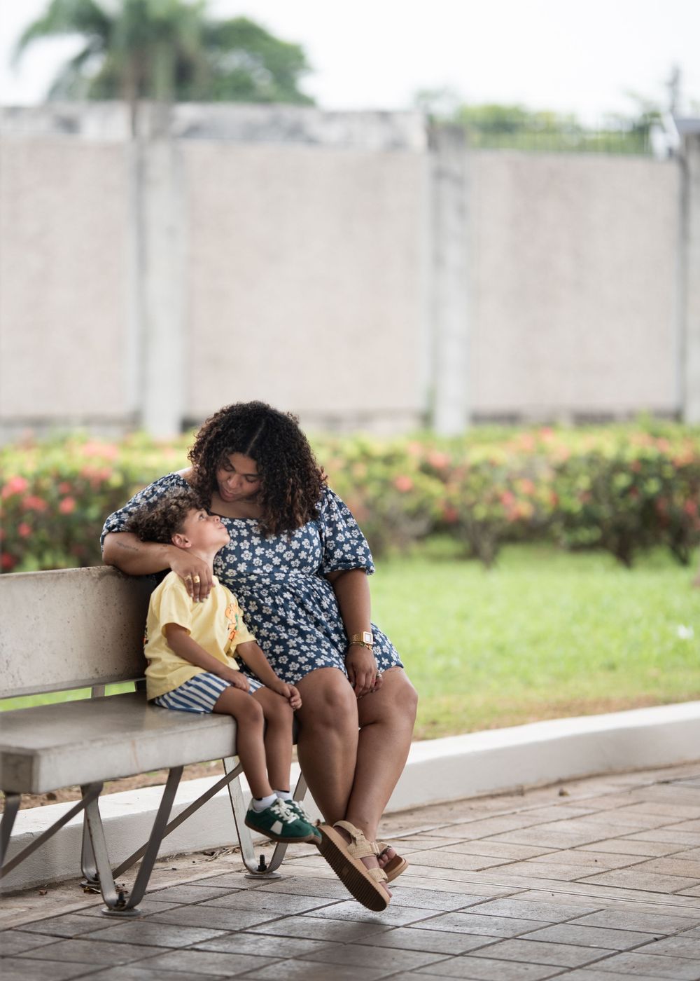 Two people sharing a tender moment on a bench in a garden setting.