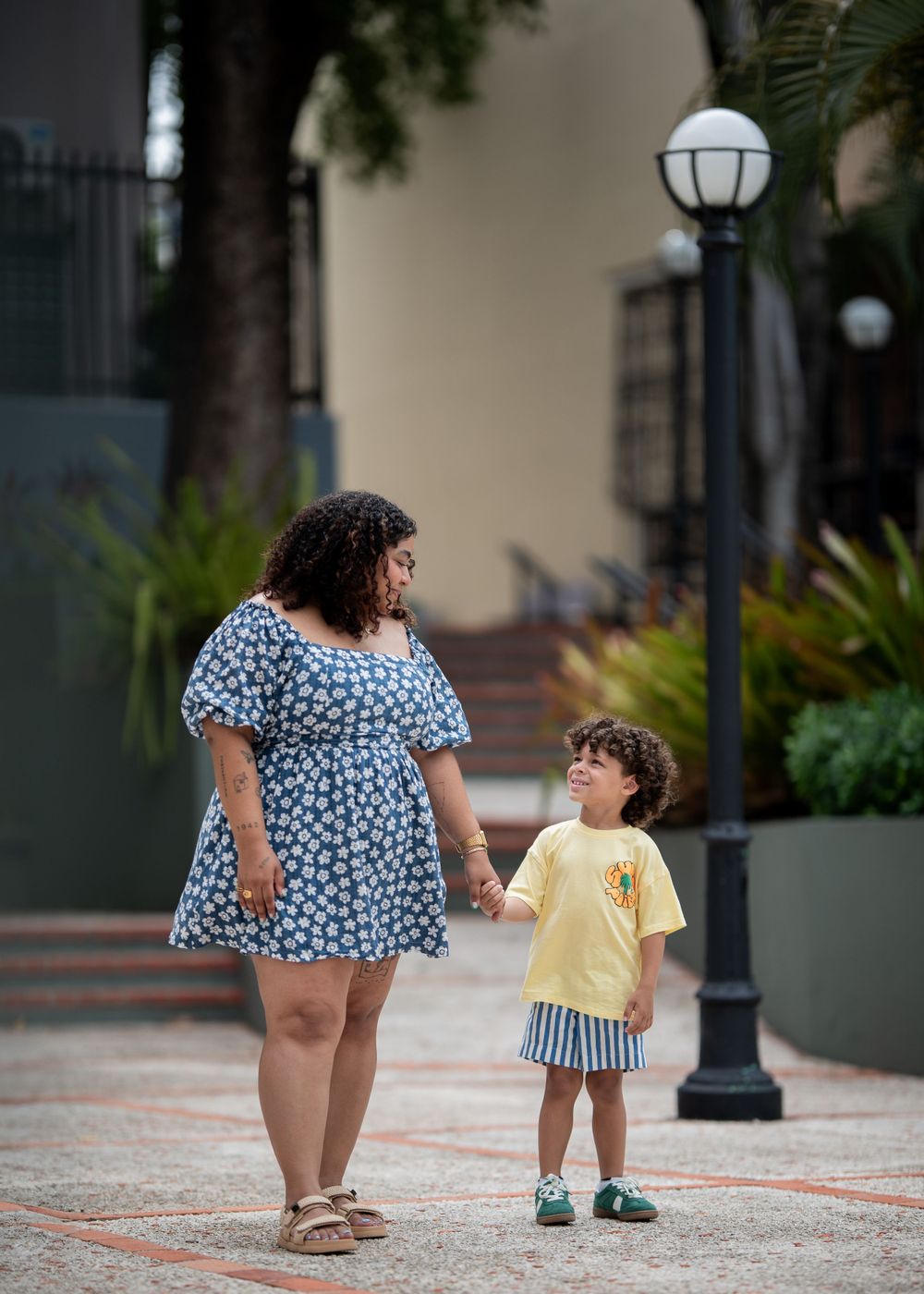 A parent and child walk together on a path with decorative lampposts.