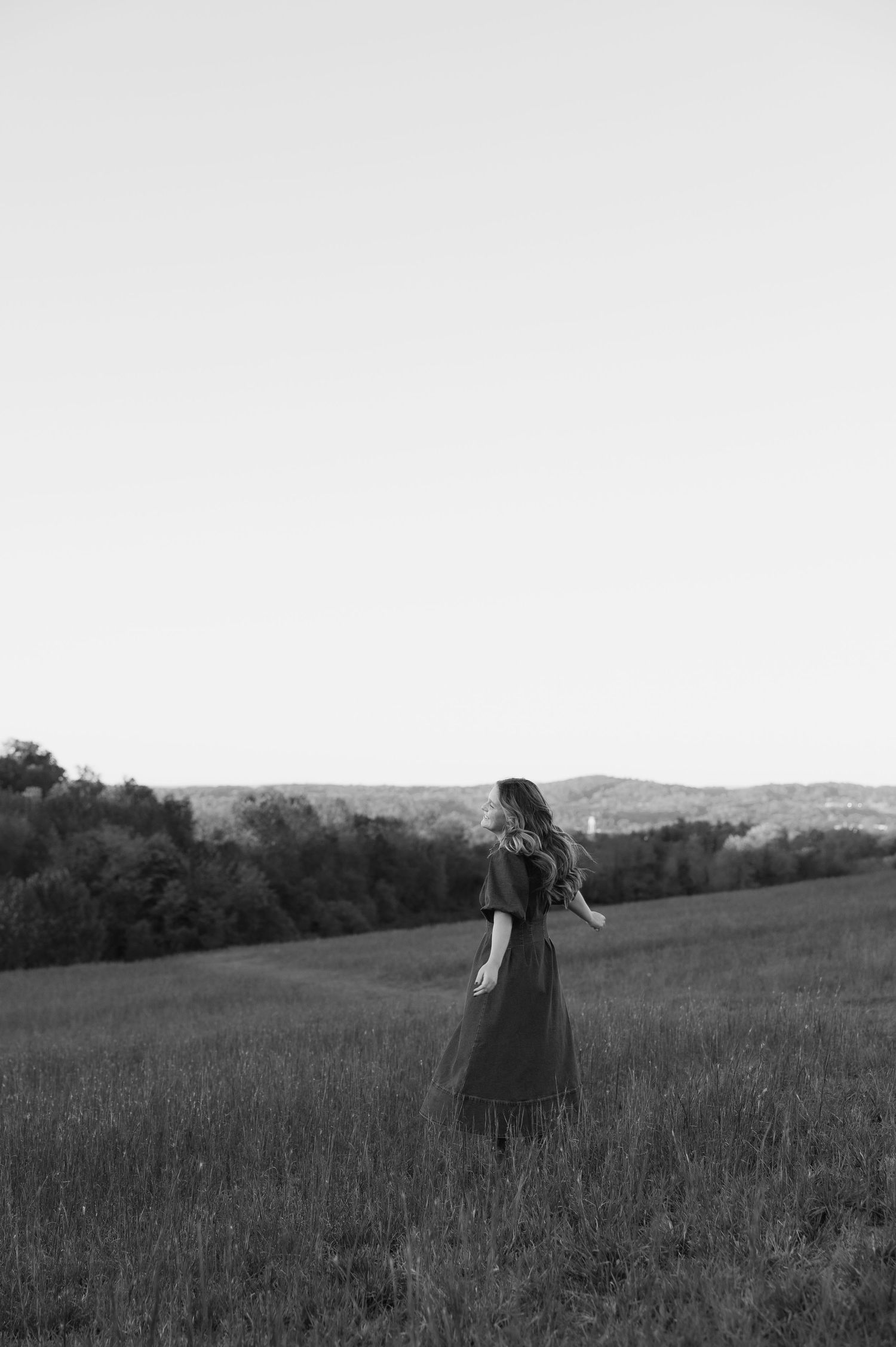 Black and white portrait series of a woman smelling flowers in a dreamy outdoor setting.