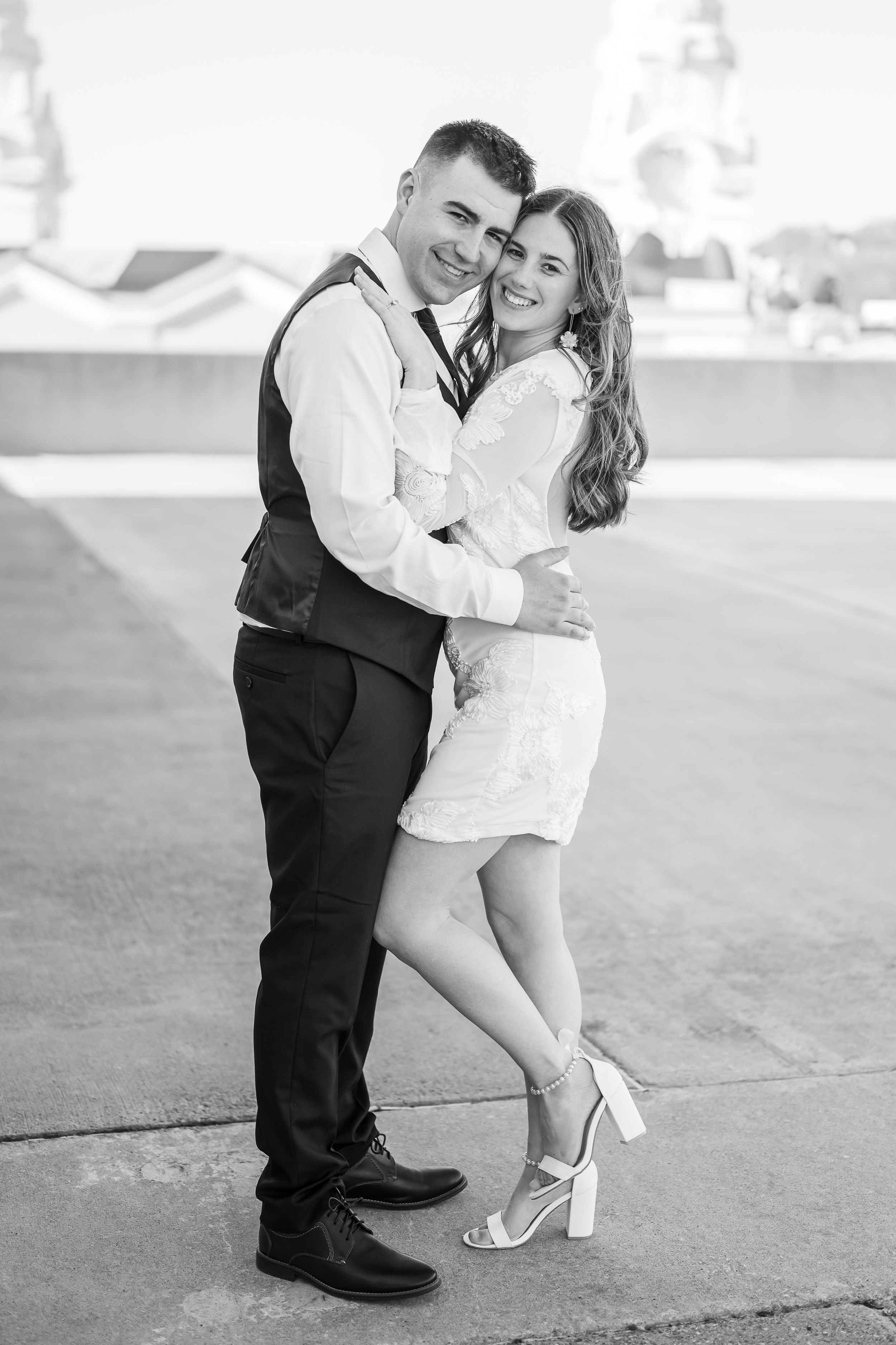 A romantic black and white portrait of a couple embracing and laughing together outdoors.