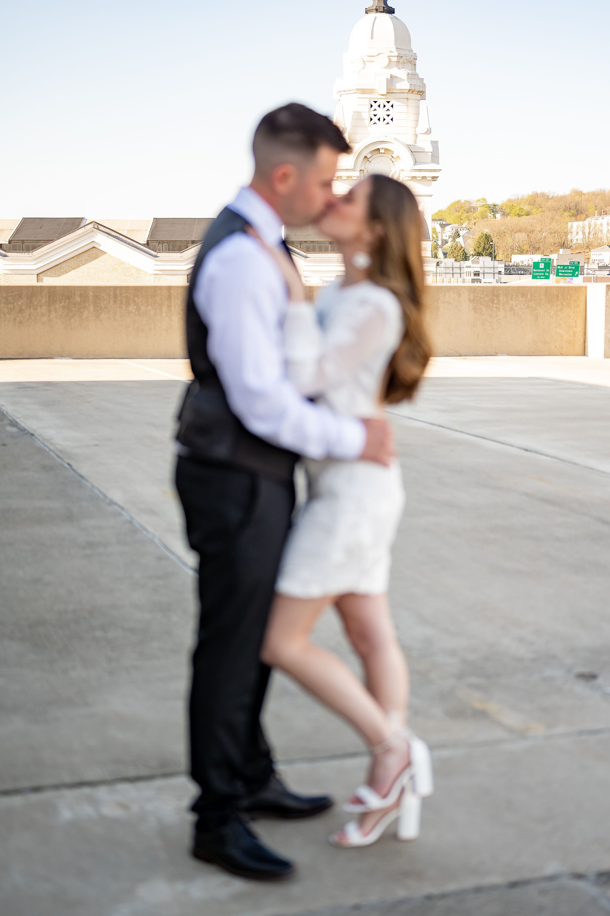 Couple sharing an intimate moment on a rooftop patio with a white church steeple visible in the background.