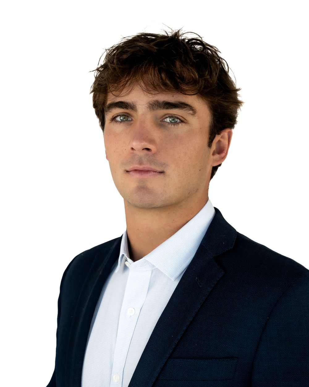 Young professional man in navy blazer and white shirt with brown hair and blue eyes on white background.
