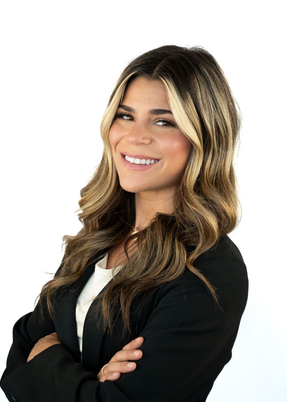 Professional headshot of a smiling woman with highlighted blonde hair wearing a black blazer, arms crossed.