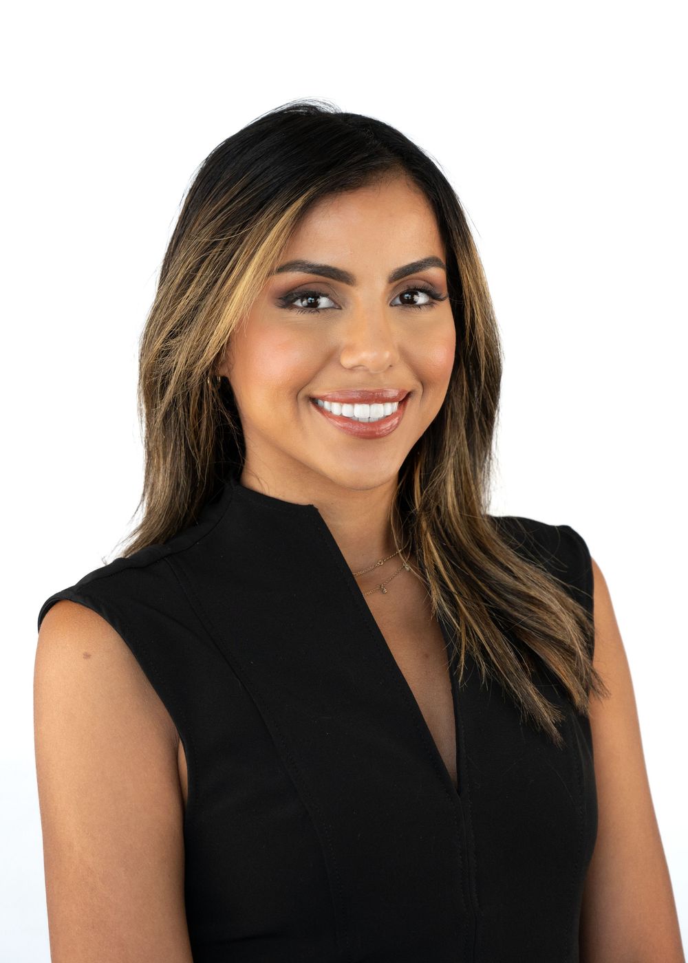 Professional headshot of a smiling woman with highlighted hair wearing a sleeveless black top.