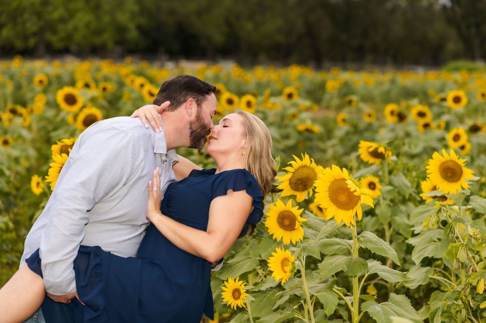 A couple shares a romantic moment in a vibrant field of blooming sunflowers during golden hour.