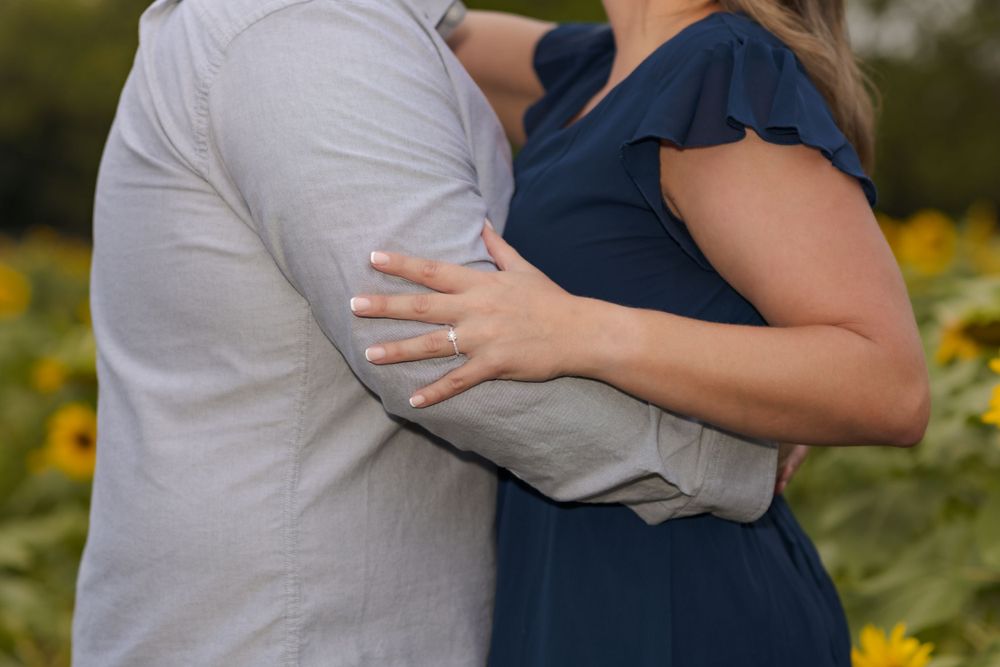 A close-up engagement photo showing a couple embracing in a sunflower field.