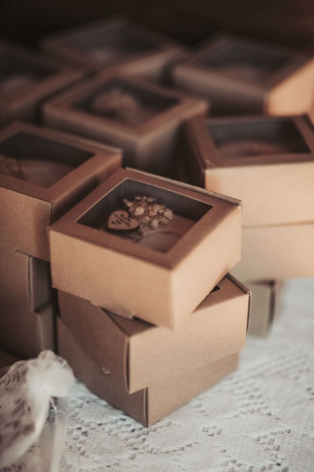 Stacked brown gift boxes with decorative designs on lace tablecloth.
