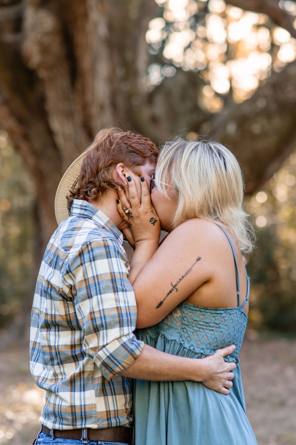 An intimate embrace captured in warm sunset lighting under a tree.