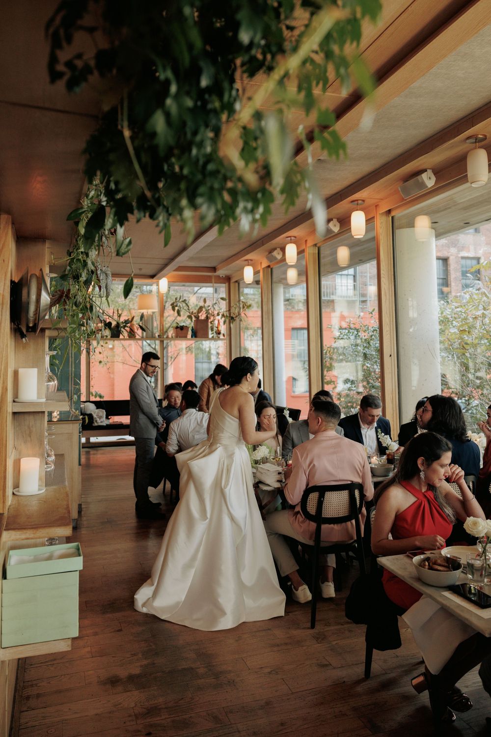 Wedding celebration in a restaurant with hanging plants and warm lighting.