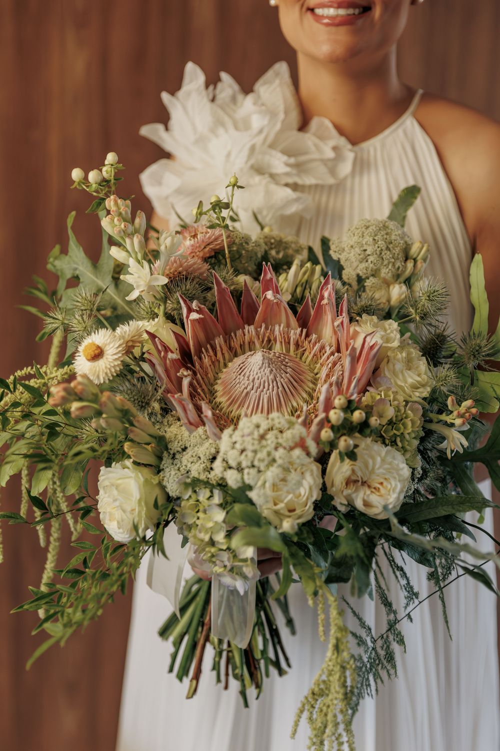 Four elegant wedding bouquets featuring white garden roses, protea flowers, and mixed greenery arranged in a rustic style.